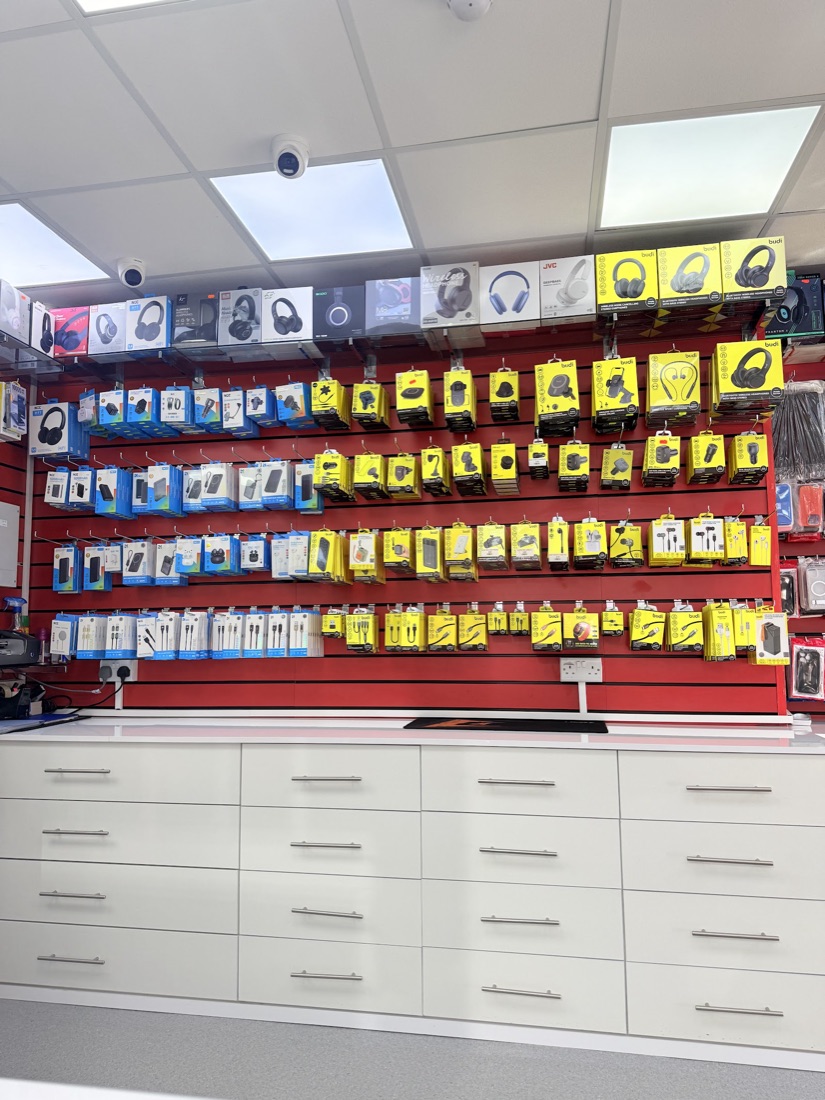 A red accessories wall at Mobile Legends stocked with chargers, cables, earphones, power banks and headphones.