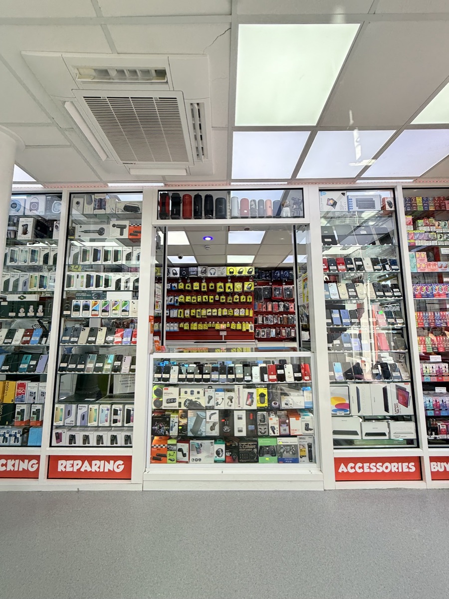 Glass display cabinets of new and used phones and accessories inside Mobile Legends, Ilford, with 'Reparing' and 'Accessories' signs.